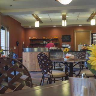 A cozy cafe with a peaceful dining area, featuring tables and chairs, warm lighting, and decorative elements.
