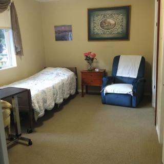 A cozy bedroom with a single bed, armchair, and nightstand.