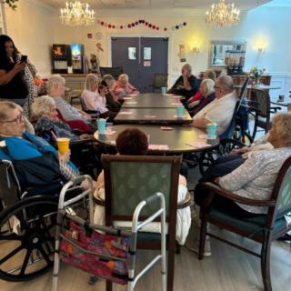 A group of elderly people gathered around a table in a nursing home setting.