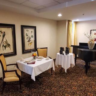 A cozy dining area with elegant decor, featuring framed artwork and a grand piano.