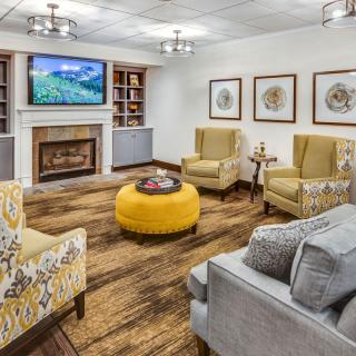 A cozy living room with a fireplace, accented with yellow furniture and wood flooring.