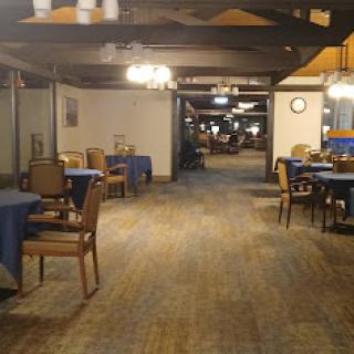 A spacious dining area in a restaurant with wooden floors and tables set for guests.
