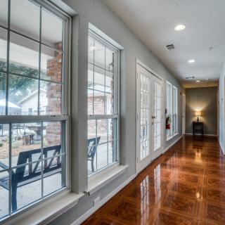 A well-lit hallway with polished wood floors and large windows.