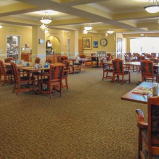 An empty dining area with neatly arranged tables and chairs on a carpeted floor.