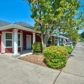 A suburban house with a well-maintained front yard and sidewalk under a clear blue sky.