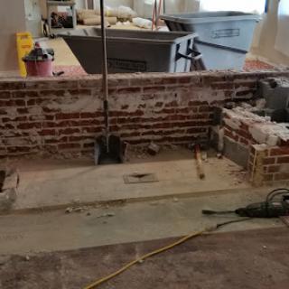 A work-in-progress construction site featuring a brick wall and various tools scattered around.