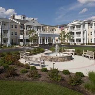 A large residential building with a landscaped garden and fountain area.