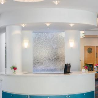 A modern office reception area with a curved desk and bright lighting.