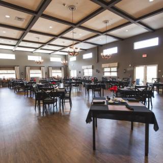 A spacious dining area with neatly arranged tables and chairs, well-lit by natural light from large windows.