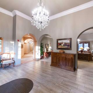 A spacious lobby area with a chandelier and reception desk, featuring arched doorways and elegant decor.