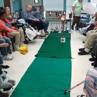Elderly residents engage in an indoor mini-golf activity at a nursing home.