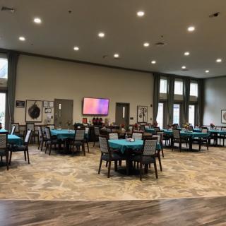A spacious event hall with round tables covered in teal cloths, neatly arranged for an upcoming gathering.