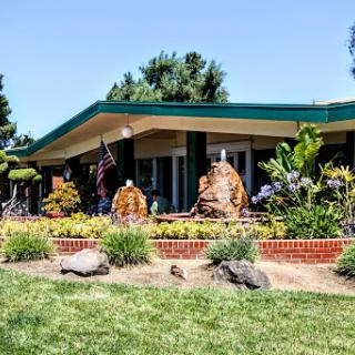 A vibrant garden landscape featuring a contemporary building with beautiful sculptures.