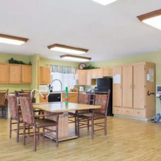 A spacious kitchen and dining area with wooden cabinets and a large table surrounded by chairs.