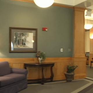 A cozy lobby with a couch, artwork on the wall, and decorative plants.
