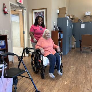 A caregiver assists an elderly woman in a wheelchair, promoting comfort and support in a community setting.