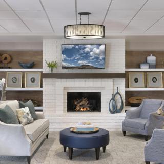A modern living room featuring a cozy fireplace, stylish furniture, and decorative shelves.