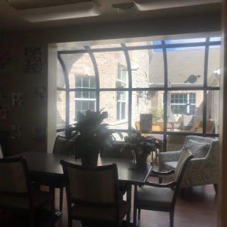A cozy dining area with tables and chairs near a large window allowing sunlight to illuminate the space.