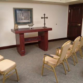 A serene chapel setting with an altar, a cross, and chairs for congregation.