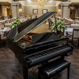 An elegant grand piano in the center of a sophisticated restaurant dining area.