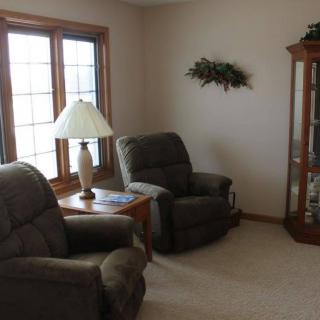 A cozy living room with two recliners, a lamp on a side table, and a decorative corner shelf.