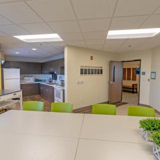 A modern kitchen and dining area with a large table and bright green chairs.