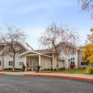 A two-story residential building with a covered entrance, surrounded by autumn trees.