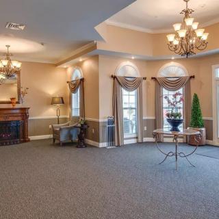 A spacious, elegantly decorated living room with chandeliers and a fireplace.