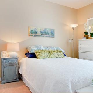A cozy bedroom with a neatly made bed, featuring a bedside table and a floor lamp.