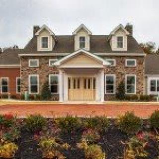 A picturesque stone and brick house with a landscaped front garden.