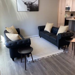 A modern living room with two dark sofas, a light rug, and a stylish wall art piece.
