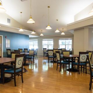 A spacious and well-lit dining room with multiple tables and chairs arranged neatly.