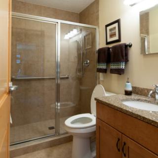 A modern bathroom with a glass-enclosed shower, toilet, and sink.