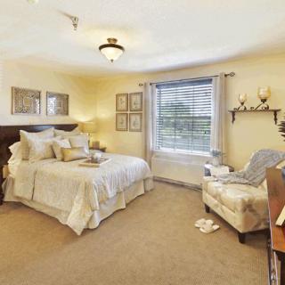 A cozy and well-decorated bedroom with a large bed, comfortable armchair, and natural light coming through the window.