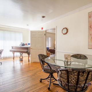 A cozy dining area with a glass table, chairs, and a piano in the background.