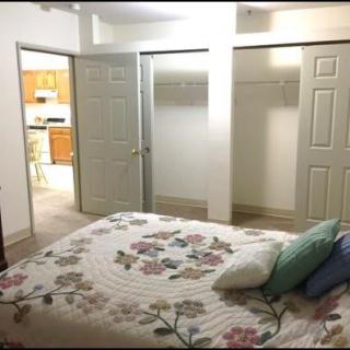 A cozy bedroom featuring a floral bedspread and multiple closet doors.