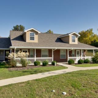A suburban house with a large porch and well-maintained lawn.