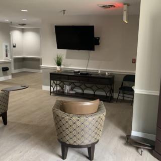 A modern living room with a wall-mounted television and comfortable chairs.