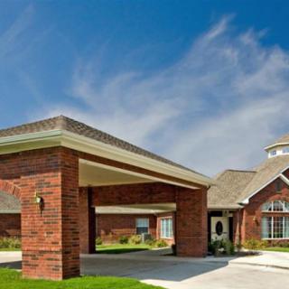 A residential brick house with a driveway and carport under a clear blue sky.