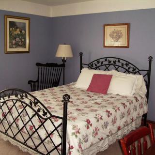 A cozy bedroom with a floral-patterned bed, metal frame, and decorative wall art.