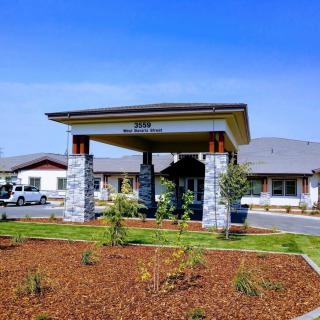 A modern building entrance with landscaped greenery on a sunny day.
