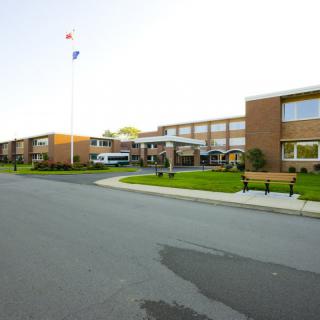 A brick school building with an American flag, benches, and adjacent road.