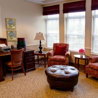 A cozy office space with a desk, chairs, and large windows.