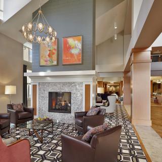 A modern living room with a cozy fireplace, elegant chandelier, and contemporary artwork.