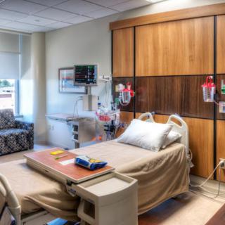 A modern hospital room equipped with a bed, medical equipment, and an IV stand.