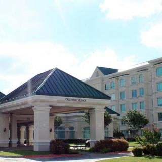 A modern hotel building with an inviting entrance and landscaped surroundings under a clear sky.
