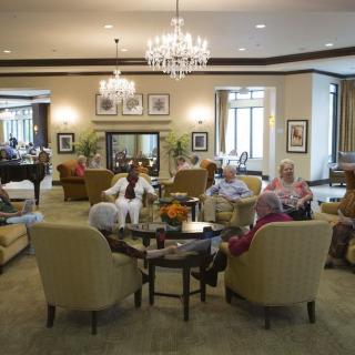 A group of seniors relaxing and conversing in a well-furnished living room.