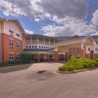 A large residential building with a spacious entrance and cloudy sky in the background.