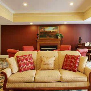 A cozy living room featuring a beige sofa with red cushions, a fireplace, and artwork on the wall.