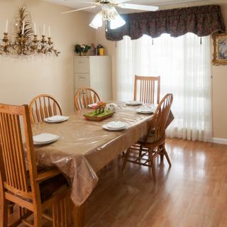 A cozy dining room with a table set for four, featuring wooden chairs and a chandelier.